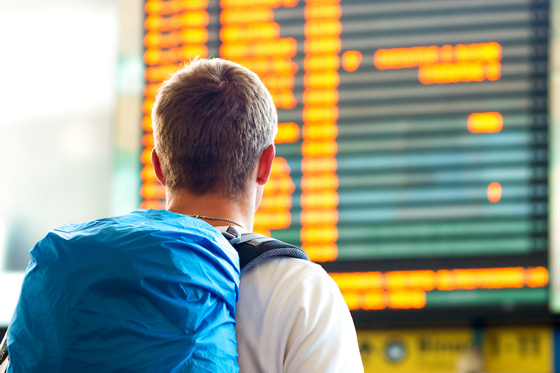 Airline passenger looks at schedule board.