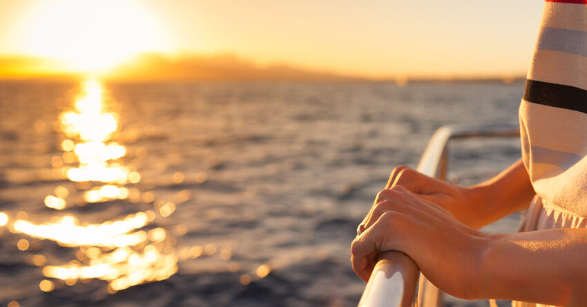 Cruise passenger holding rail with sunset in background