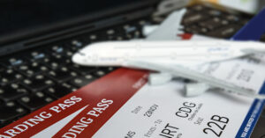 Two boarding passes with a white model airplane on a laptop keyboard.