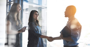 Handshake greeting between business women, entrepreneur and accountant banker with tablet and portfolio. Happy female and male corporate professionals meeting, welcoming or making deal on investment.