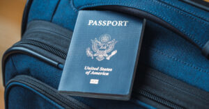 A blue American passport sitting on top of a blue suitcase